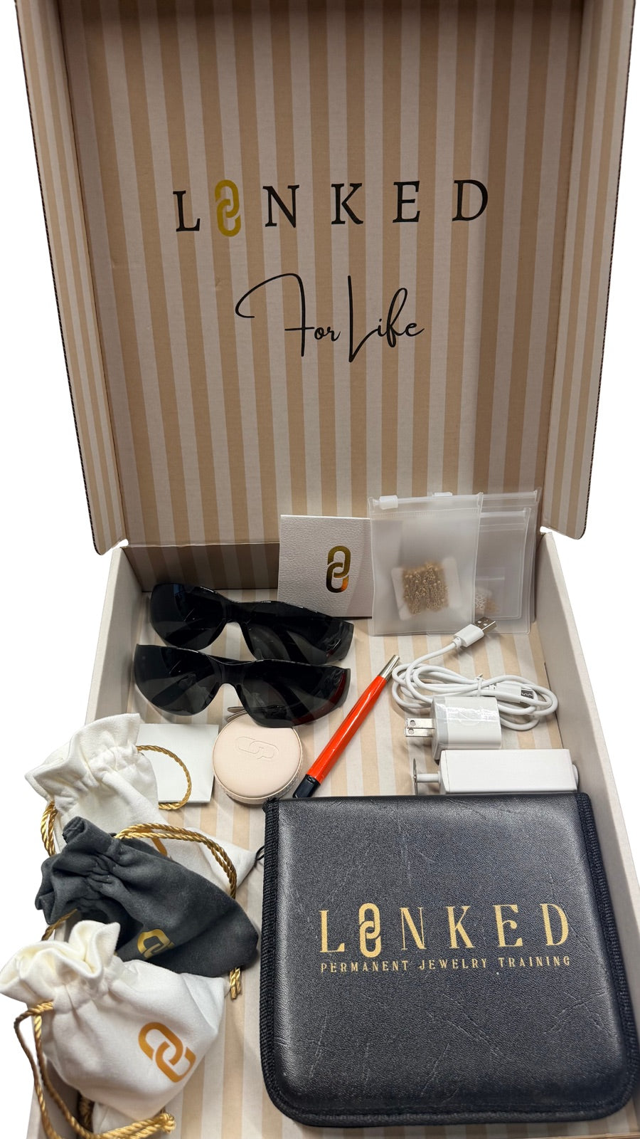 An open LINKED starter kit box with safety glasses, jump rings, a sharpener and the LINKED tool pouch